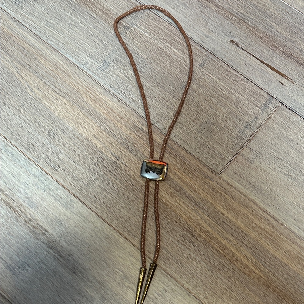 western-style bolo tie featuring a covered wagon emblem.